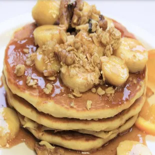 a stack of pancakes topped with bananas and nuts