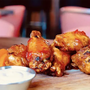 a pile of chicken wings with a side of dip