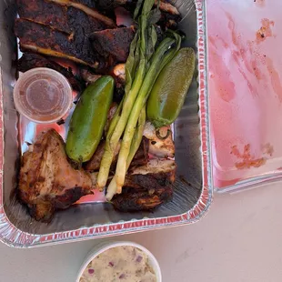 Marinated ribs and chicken plate with potato salad and peppers.