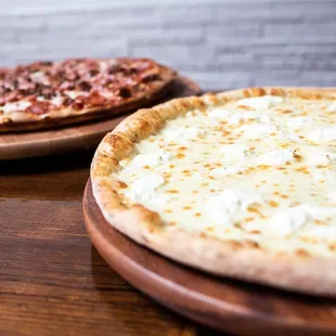 two pizzas on wooden platters