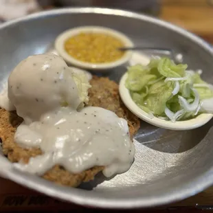Chicken fried steak round with corn and cucumbers with onions.