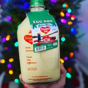 a person holding a bottle of egg nog