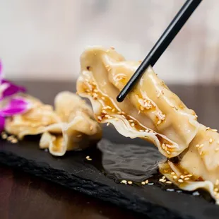 a person holding chopsticks over a plate of food