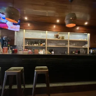 a bar with stools and a television