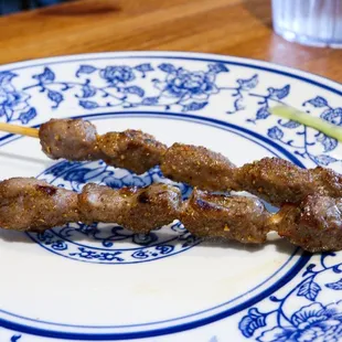 two skewers of meat on a plate