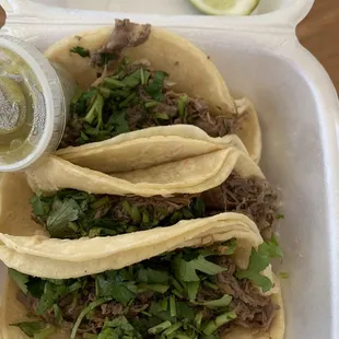 Barbacoa tacos I asked for no onions but they do come with onion and cilantro. Also with a side of green salsa and lime.