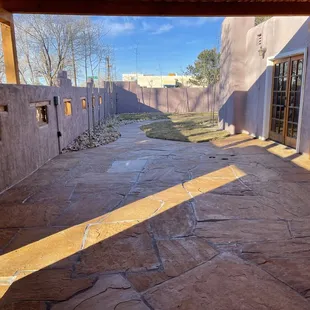 Flagstone patio using larger peach select under new pergola photographed in winter with newly laid dormant sod, aspens, drip, and cobble