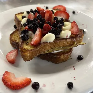 a plate of french toast with strawberries and blueberries