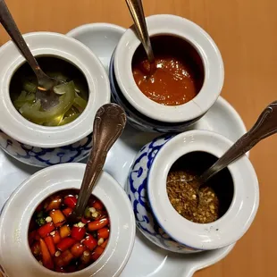Table condiments: jalapenos in vinegar, sriracha, thai chiles in fish sauce, and crushed peppers