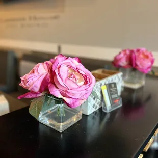 pink roses in clear vases on a black table