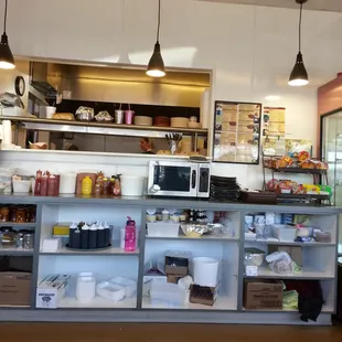 a counter with a microwave and shelves of food