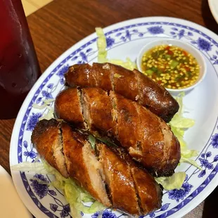 a plate of grilled sausages with lettuce and dipping sauce
