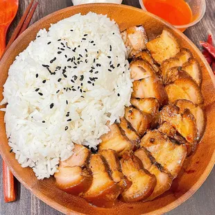 a bowl of rice, chicken, and chopsticks