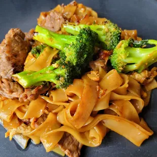 a plate of noodles with meat and broccoli