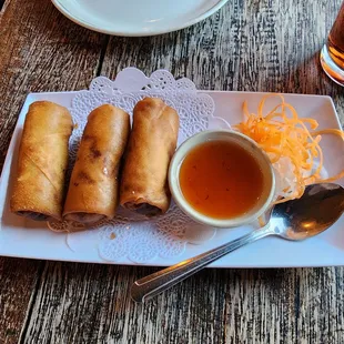 a plate of spring rolls with dipping sauce