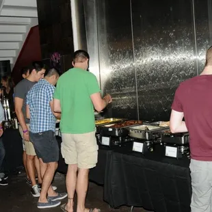 a group of people standing around a buffet