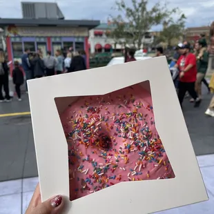 a pink frosted donut with sprinkles