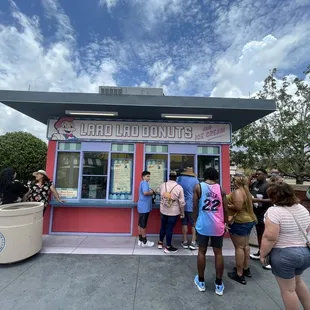 a group of people standing in front of a donut shop