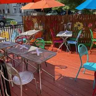 tables and chairs on a deck with umbrellas