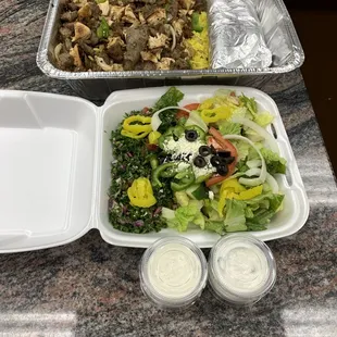 a salad in a container and a container of dressing