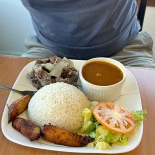 Bistec encebollado, arroz blanco, habichuelas y maduros.