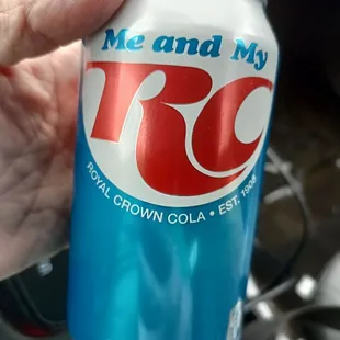 a hand holding a can of r c