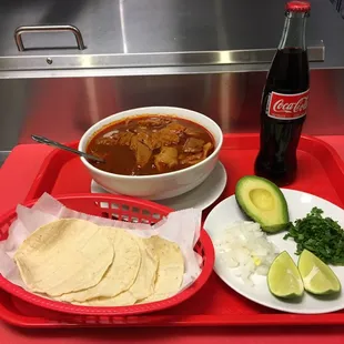  bowl of chili, tortilla, avocado, and a bottle of coke