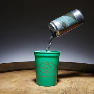 a beer being poured into a green cup