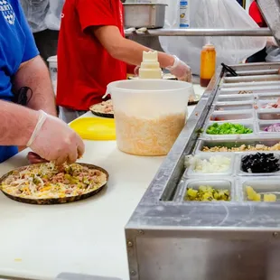 a man putting toppings on a pizza