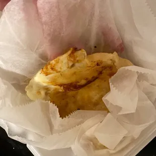 a person holding a sandwich in a paper wrapper