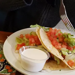 Two chicken tacos with a side of sour cream