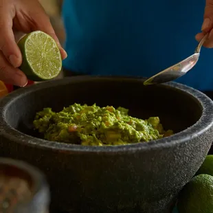 a person scooping guacamole into a bowl