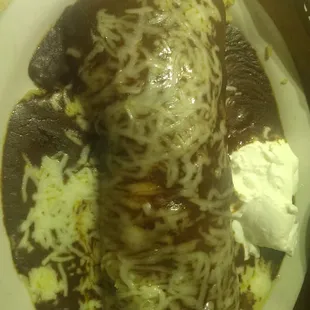 Wet burrito with mole stuffed with shredded chicken rice beans n toped wirh cheese