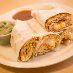 two burritos on a plate with a side of guacamole