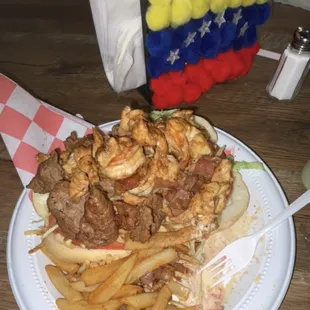 Pepito Mar Y Tierra Steak Shrimp Chicken Lettuce Tomatoes and gouda cheese on a bun with Season fries and bacon sauce on the side