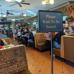 a restaurant with a sign that says please wait to be seated