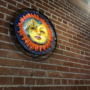 a sun face on a brick wall