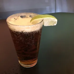 a glass of beer with a lime wedge