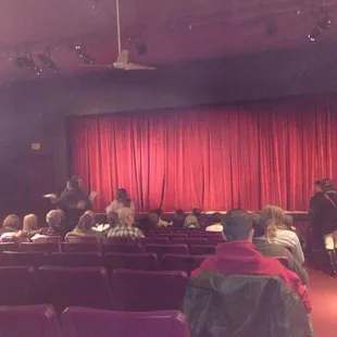 people sitting in chairs in front of a red curtain