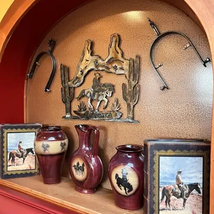 a shelf with three vases and a picture of a cowboy