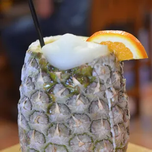 a pineapple drink with an orange slice