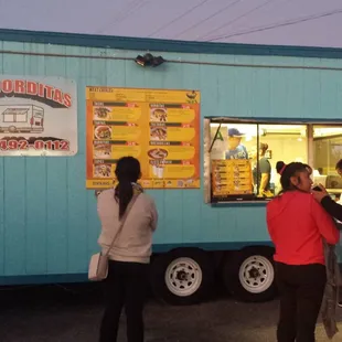 a group of people standing in front of a food truck
