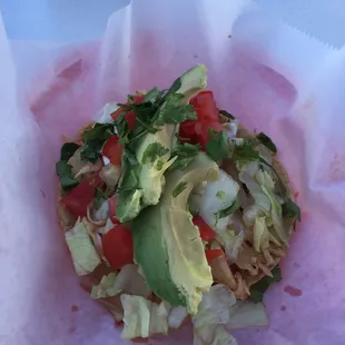 Chicken taco with lettuce, cilantro, tomato, and sour cream.