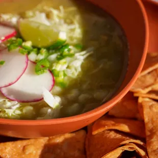 Pozole verde with shredded chicken, hominy, corn chips, cabbage, onions, radish, serrano chiles, lime, and chili oil sauce (optional).