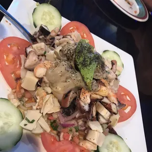 a plate of salad with cucumbers and tomatoes