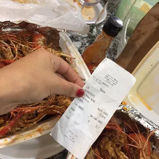 a woman&apos;s hand holding a receipt in front of a plate of shrimp