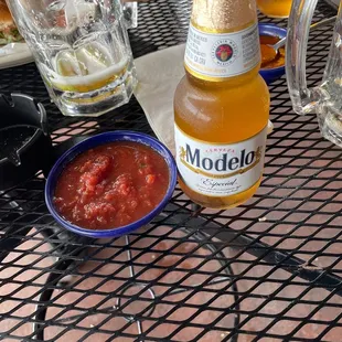 a bottle of modelo next to a bowl of salsa