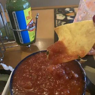 a person dipping a tortilla into a bowl