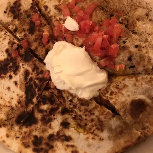 A quesadilla with cheese, tomatoes, and sour cream.