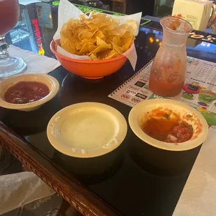 three bowls of salsa and a bowl of chips